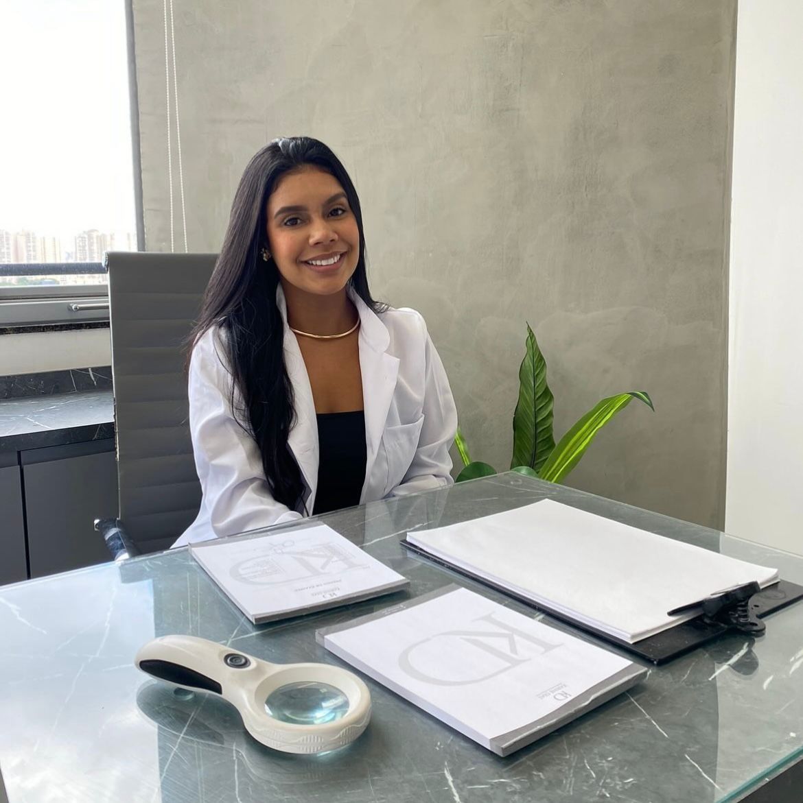 Dra. Karine Dias no consultório, de jaleco