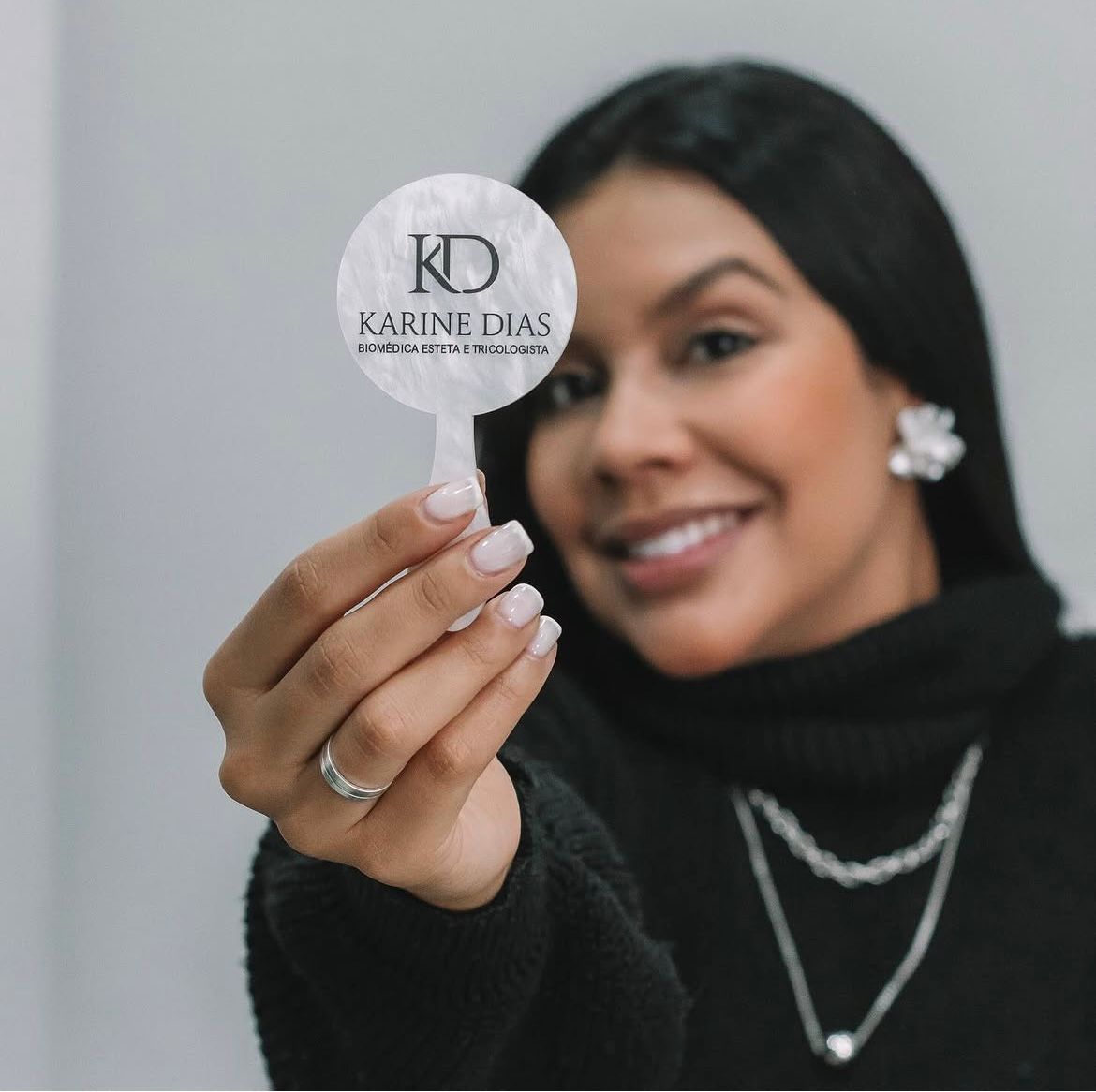 Dra. Karine Dias segurando o logo KD